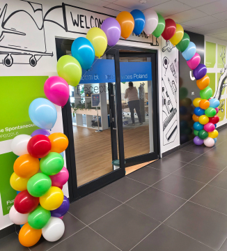 Kolorowe balony z helem ułożone w łuk jako dekoracja wejścia do firmy z okazji urodzin