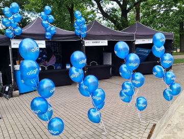 Balony z nadrukiem napełnione helem i powiązane w bukiety Balony z helem i nadrukiem jako dekoracja stanowiska promocyjnego na wydarzeniu we Wrocławiu