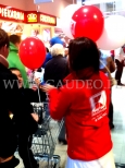 Hostessa rozdaje balony z nadrukiem założone na patyczki.