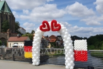 Brama z balonów z flagami Polski i Niemiec.