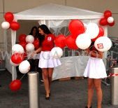 Hostessy z balonami na patyczkach przed sklepem.