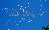 Wypuszczone balony z helem odlatują nad miastem.