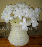 Biało kremowa kolorystyka balonowego wazonu wypełnionego kwiatami.