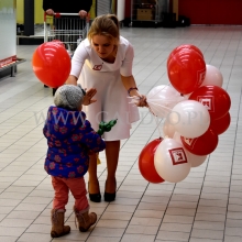 Hostessa daje dziecku balon na patyczku.