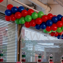 Girlandy z balonów podwieszone nad linią kas w hipermarkecie Auchan.